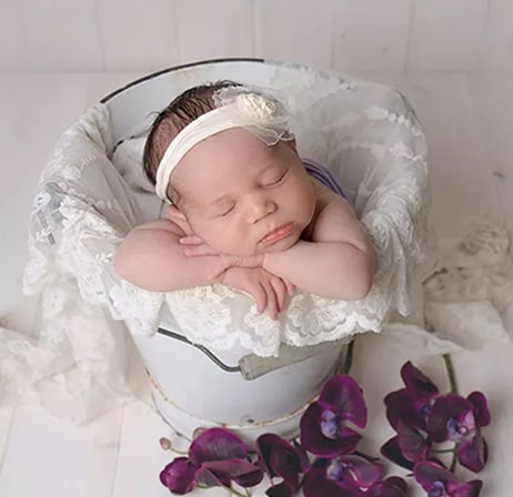 Newborn baby in basket head resting on its hands by Haywards Heath photographer