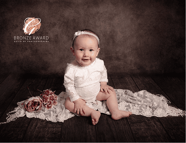 Bronze award winning photo of baby sitting on decorative fabric by Sussex photographer studio