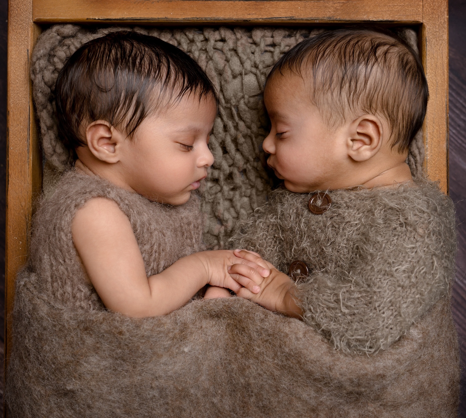 Photo of twins laying facing each other holding hands by East Grinstead photographer
