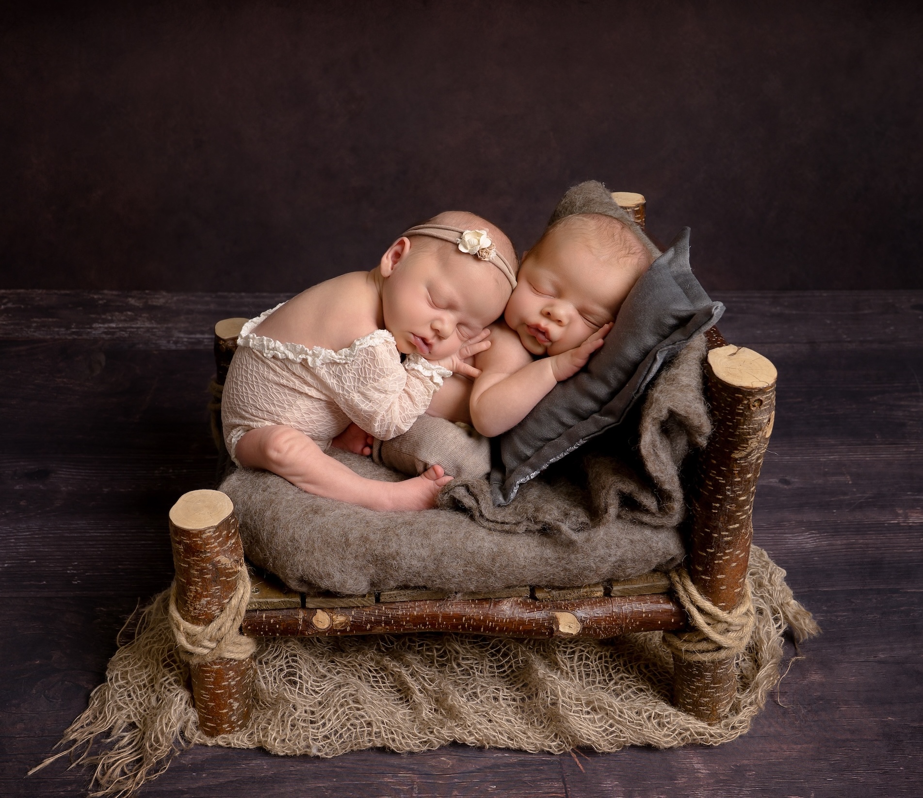 Twins laying gently on one another on wooden chair by Sussex photography studio