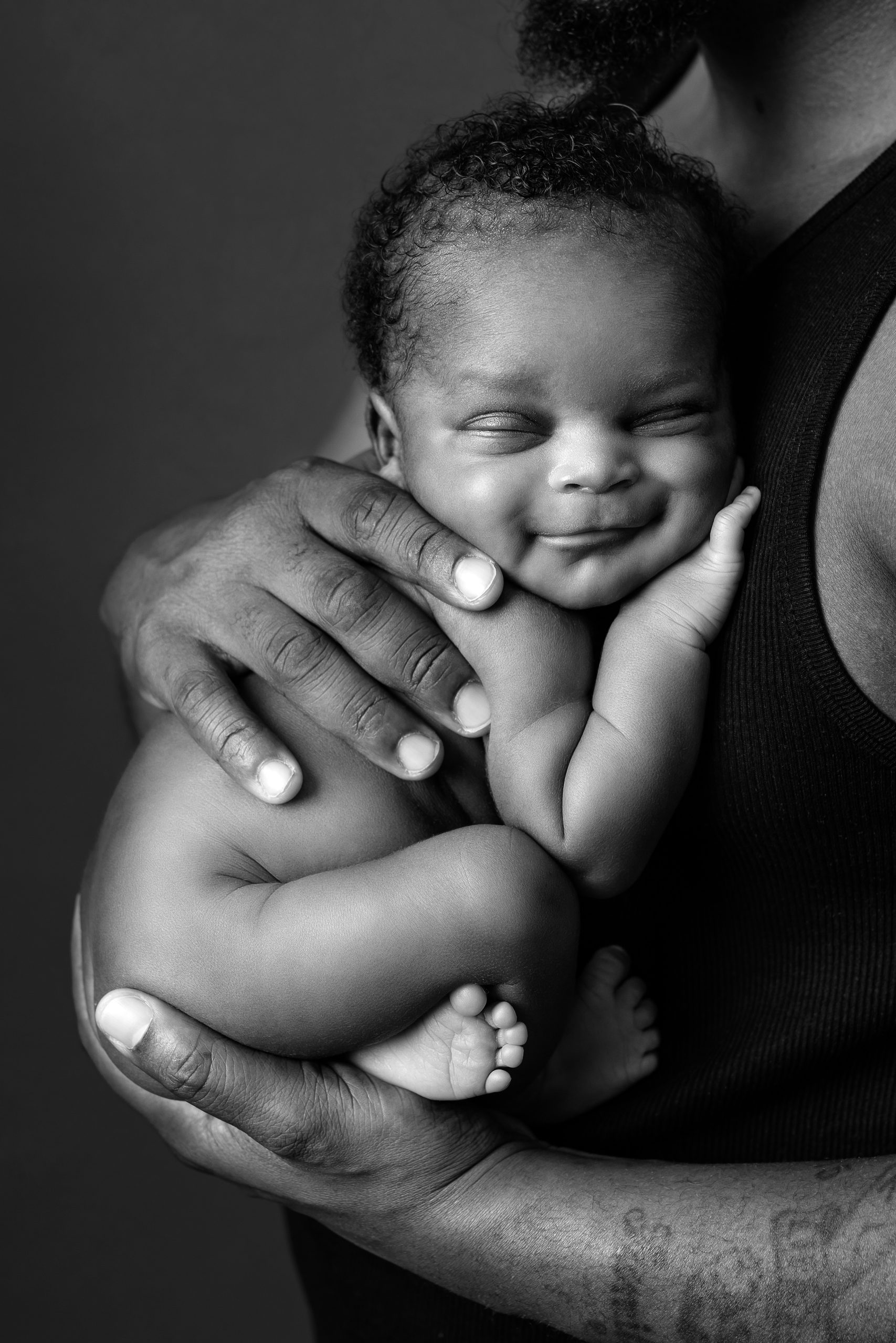 Newborn being held by dad against chest by Sussex photographer