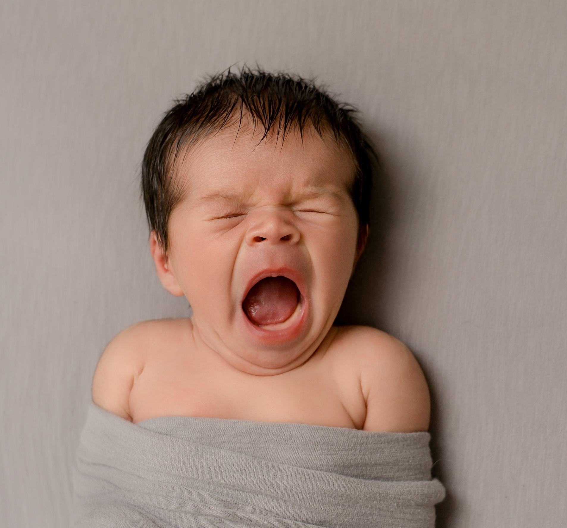 Baby wrapped in blanket yawning by East Grinstead photographer