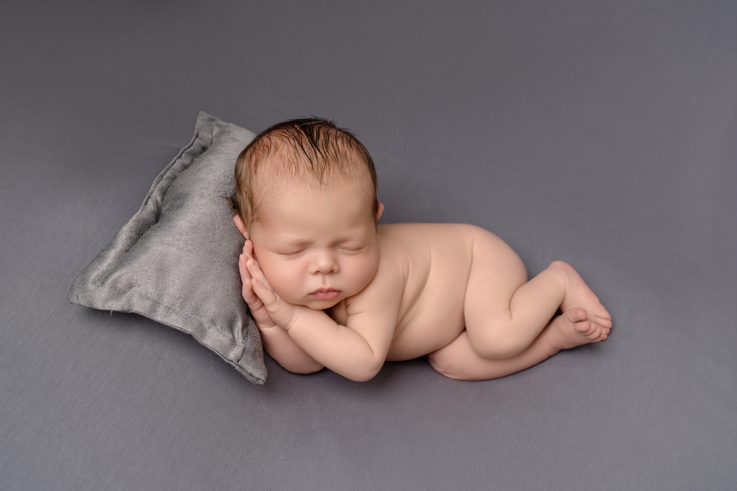 baby laying on side with head on pillow by Horley photographer