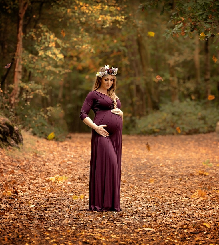 Lady in forest holding baby bump in maternity photoshoot by Horley photographer