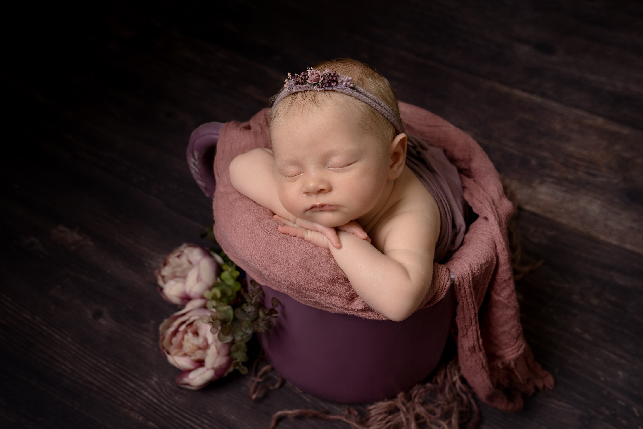 Newborn Baby laying in basket with headband and flowers by west sussex photography studio