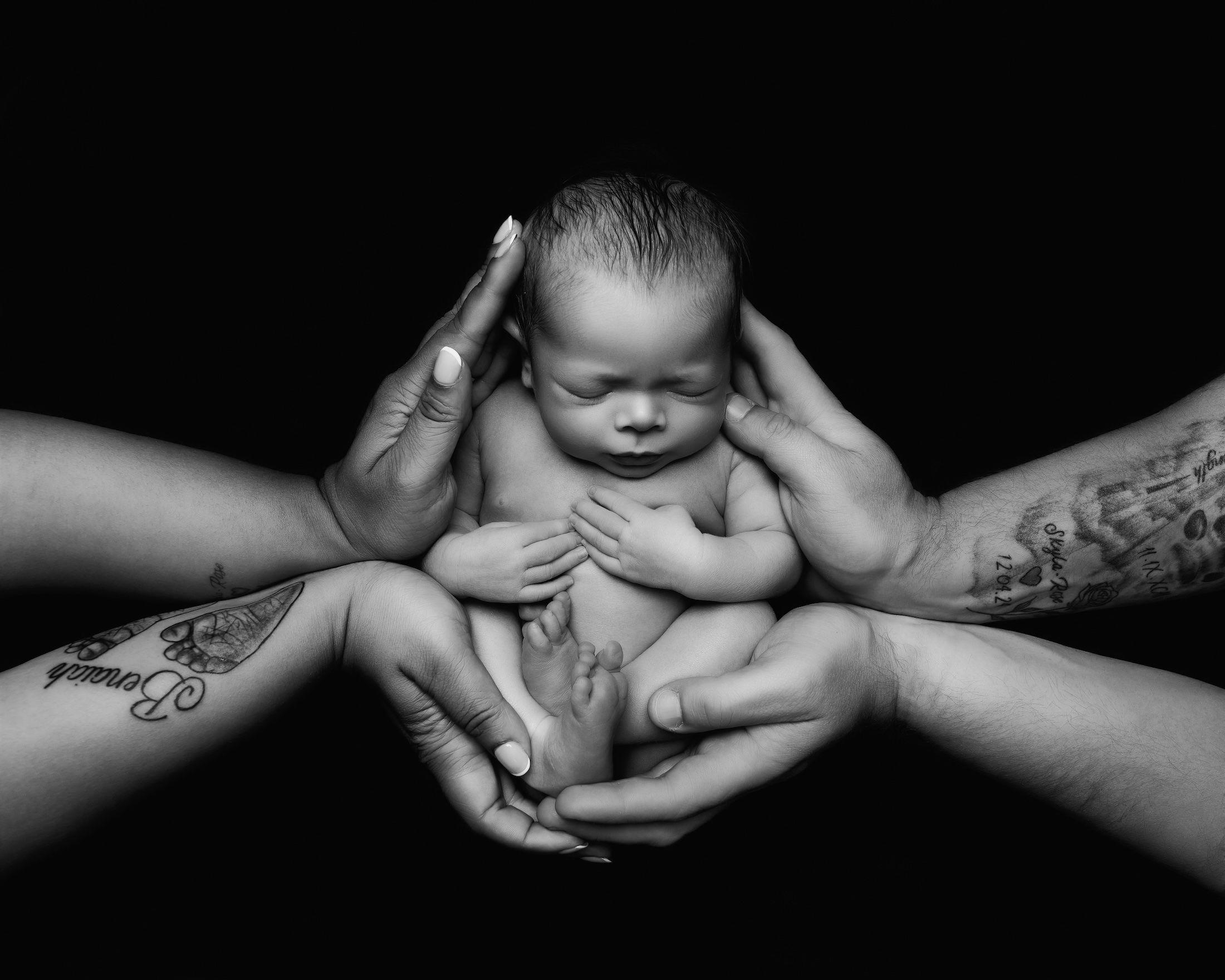Newborn baby being held by both parents hands on either side by Horley photgrapher