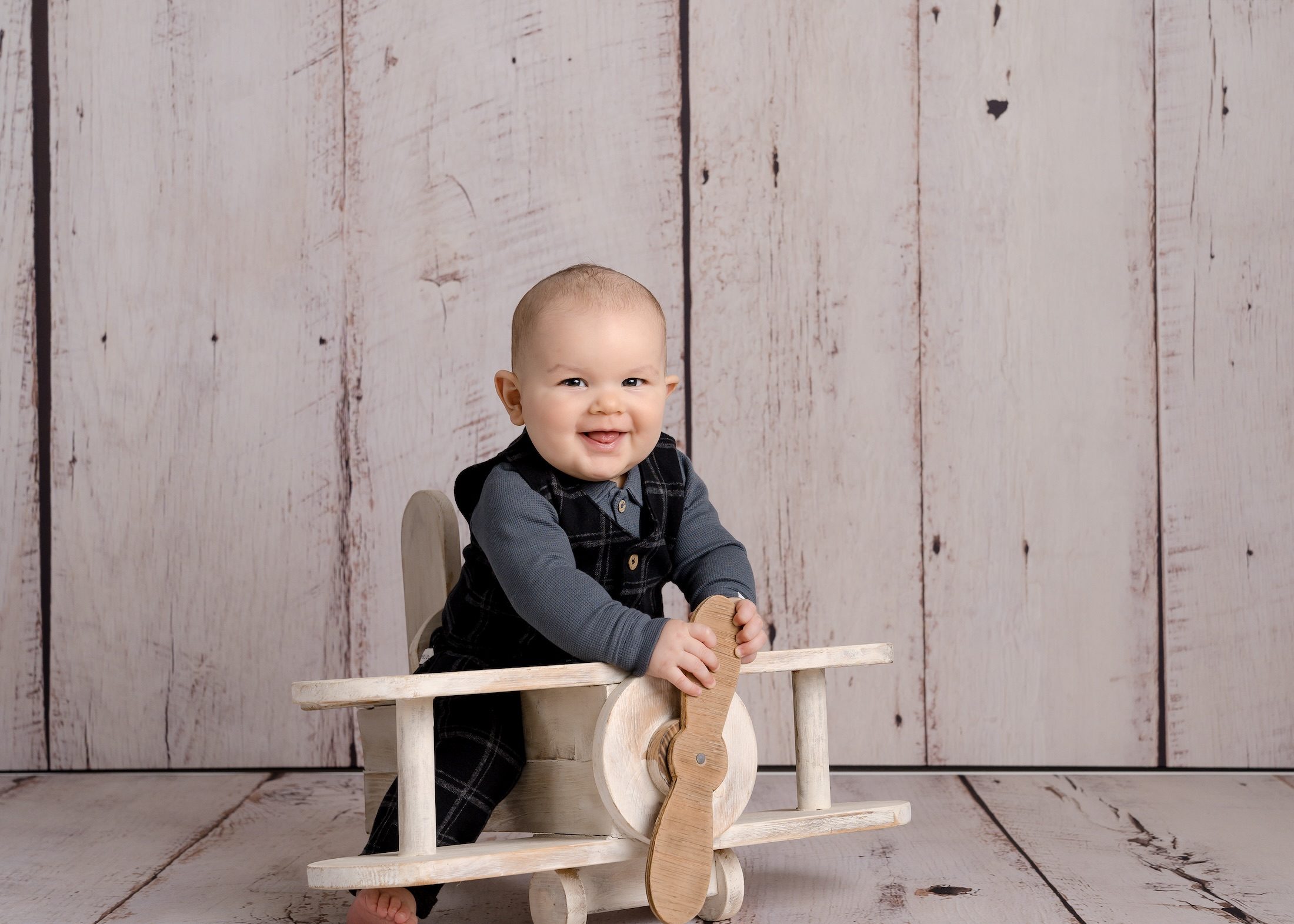 Baby sitting on wooden airplane prop by Crawley photography studio